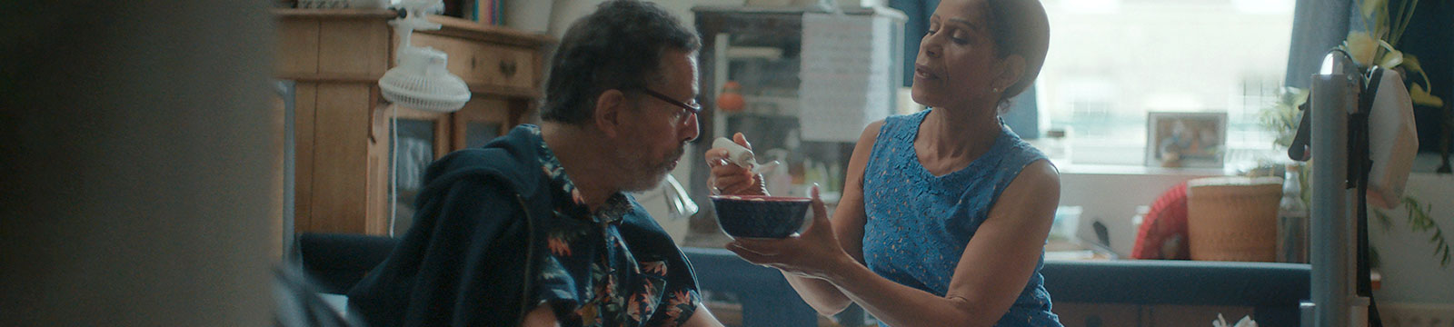 Uma mulher alimenta o marido sentado na cadeira de rodas. Uma mulher alimenta o marido sentado na cadeira de rodas.